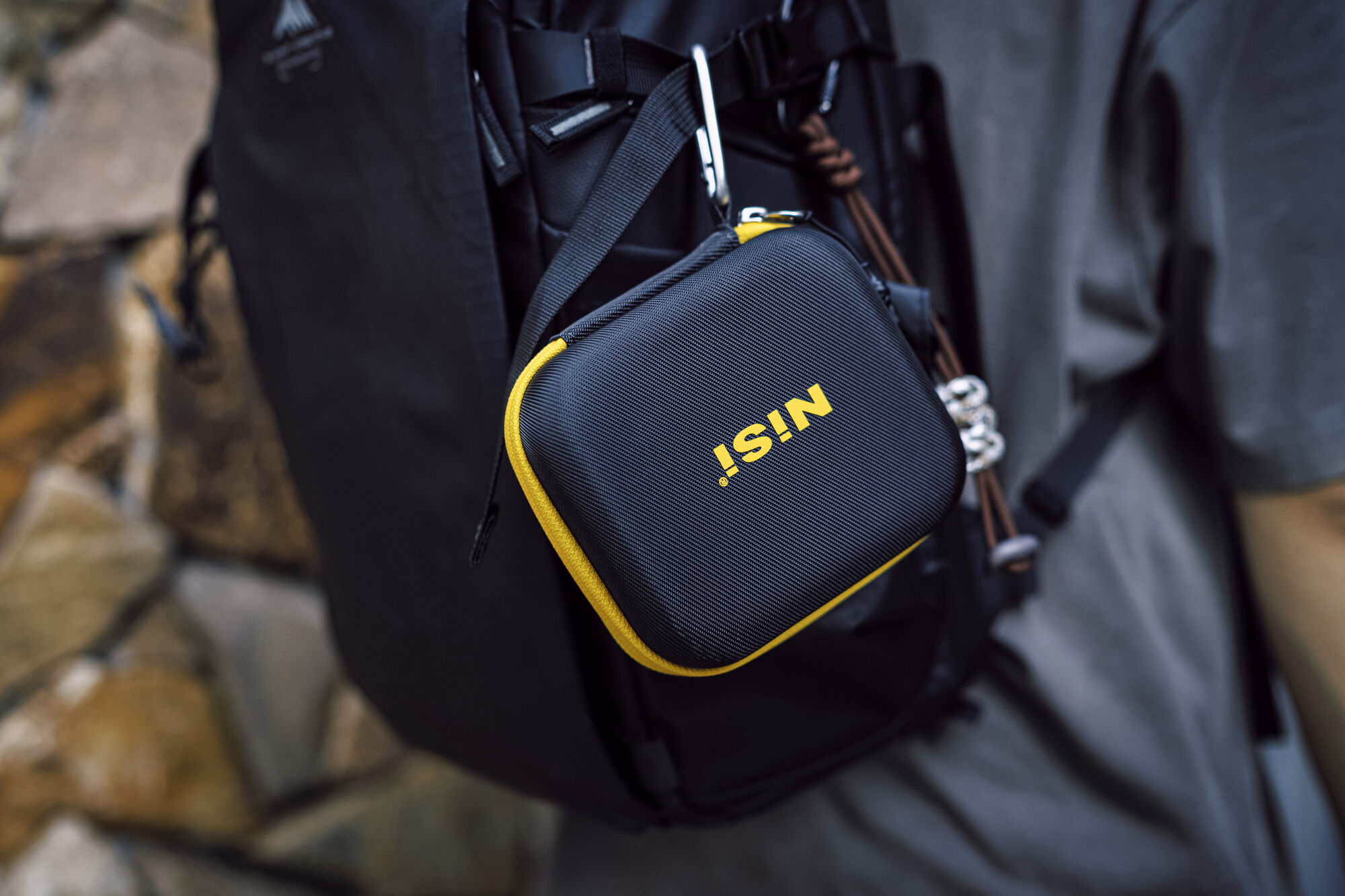A NiSi Caddy III filter pouch clipped by its carabiner to the strap of a camera backpack on location