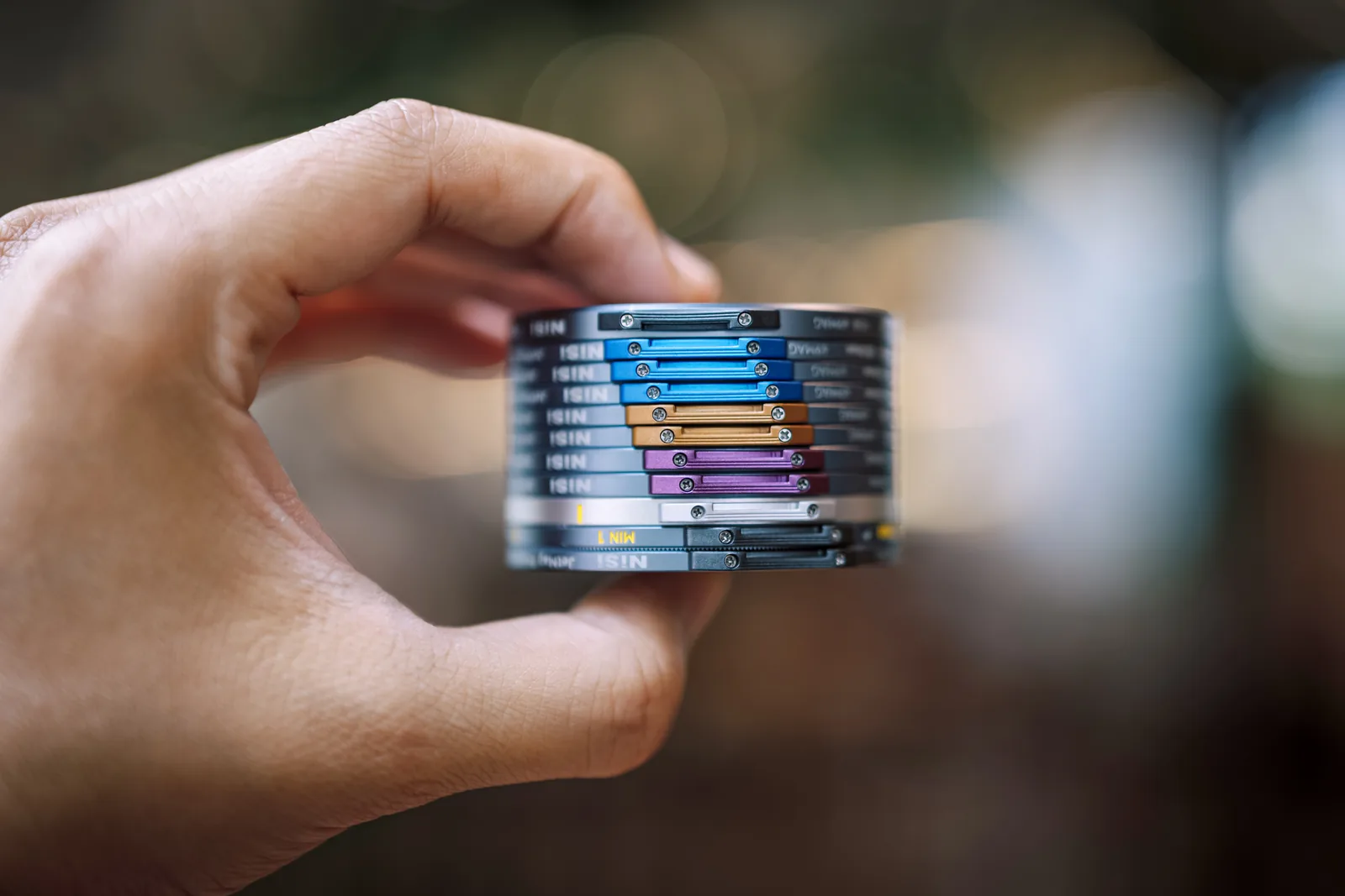 A stack of NiSi JetMag Pro 49MAG filters held in one hand, each with a colored handle
