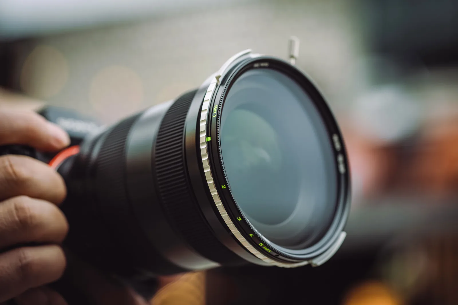 A hand holding a camera with a NiSi True Color VND/PL fitted to the lens