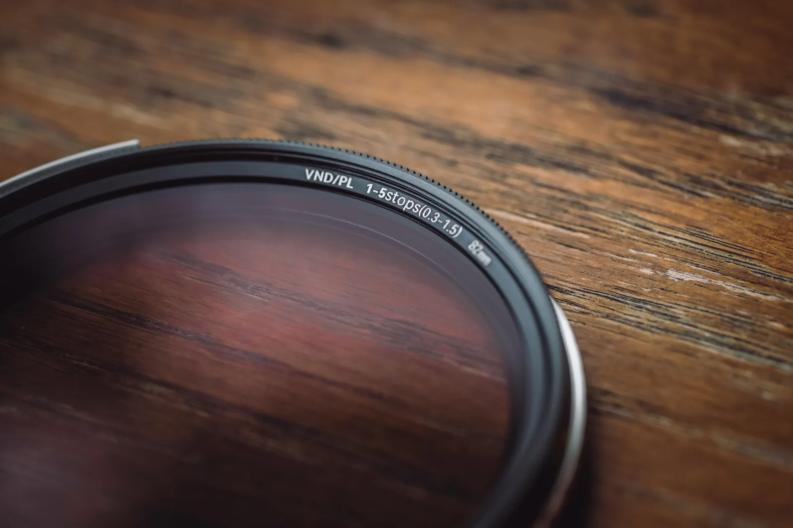 A NiSi True Color VND/PL filter lying on a wooden table, its VND/PL 1-5 stops marking on the rim
