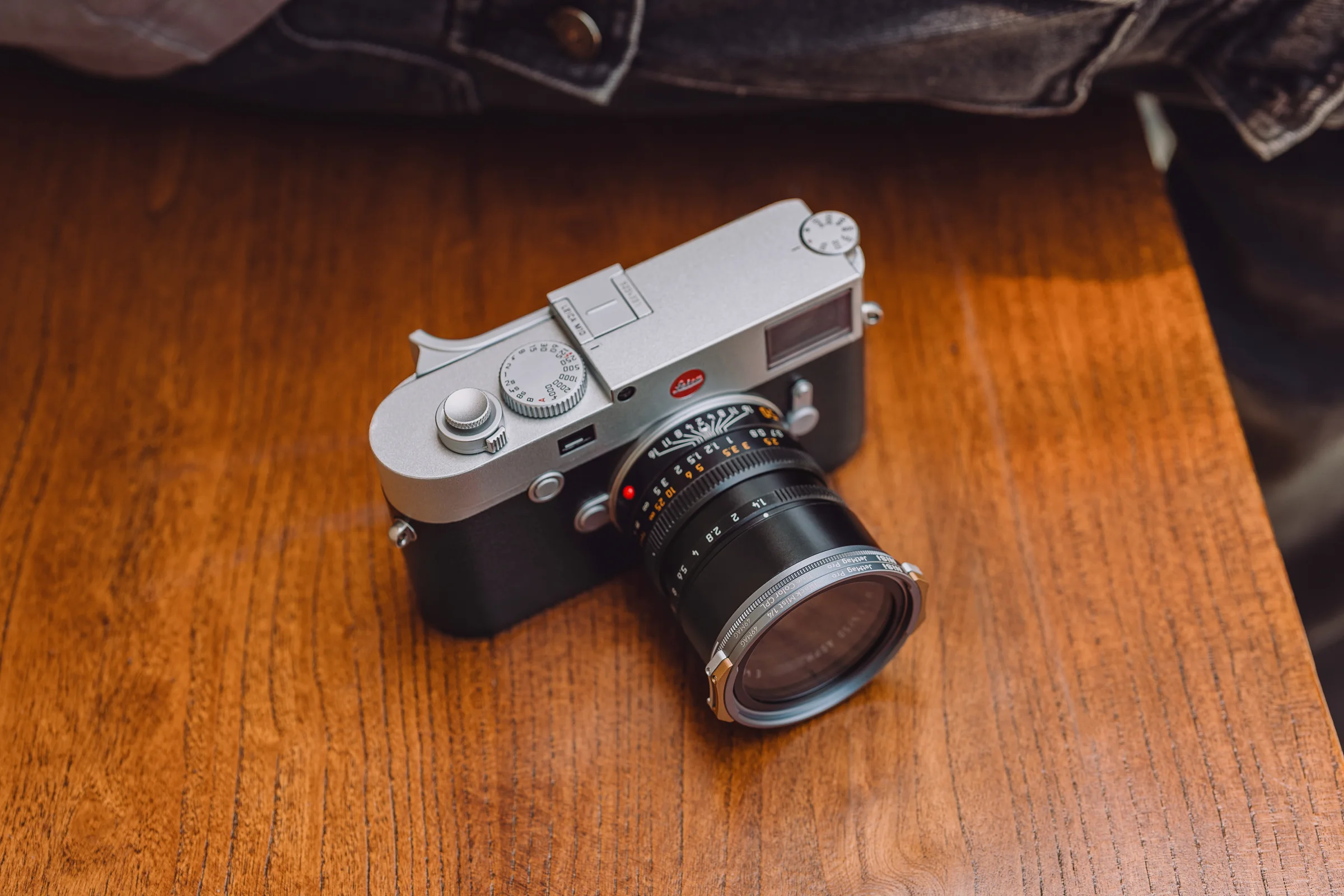 A Leica rangefinder with a NiSi JetMag Pro 49MAG filter fitted, on a wooden table