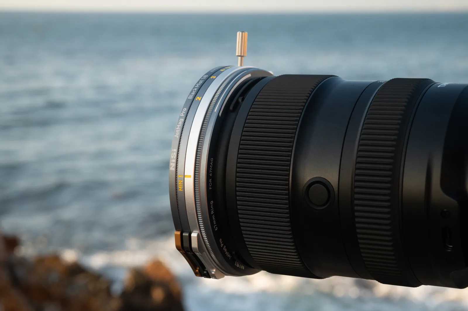 A lens with stacked 67MAG filters beside the ocean