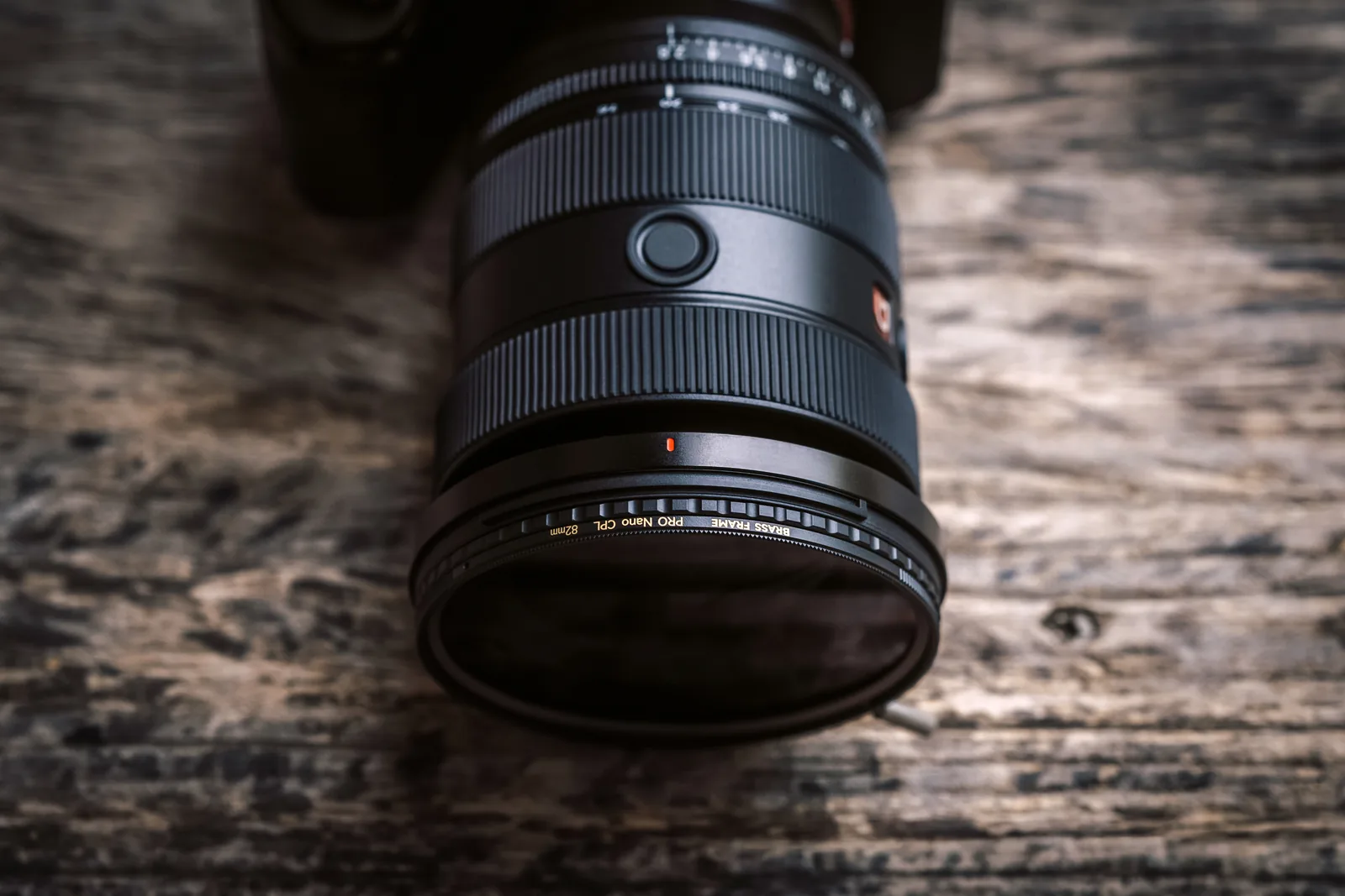 Looking down on the knurled frame of the CPL fitted to a Sony lens on a wooden table