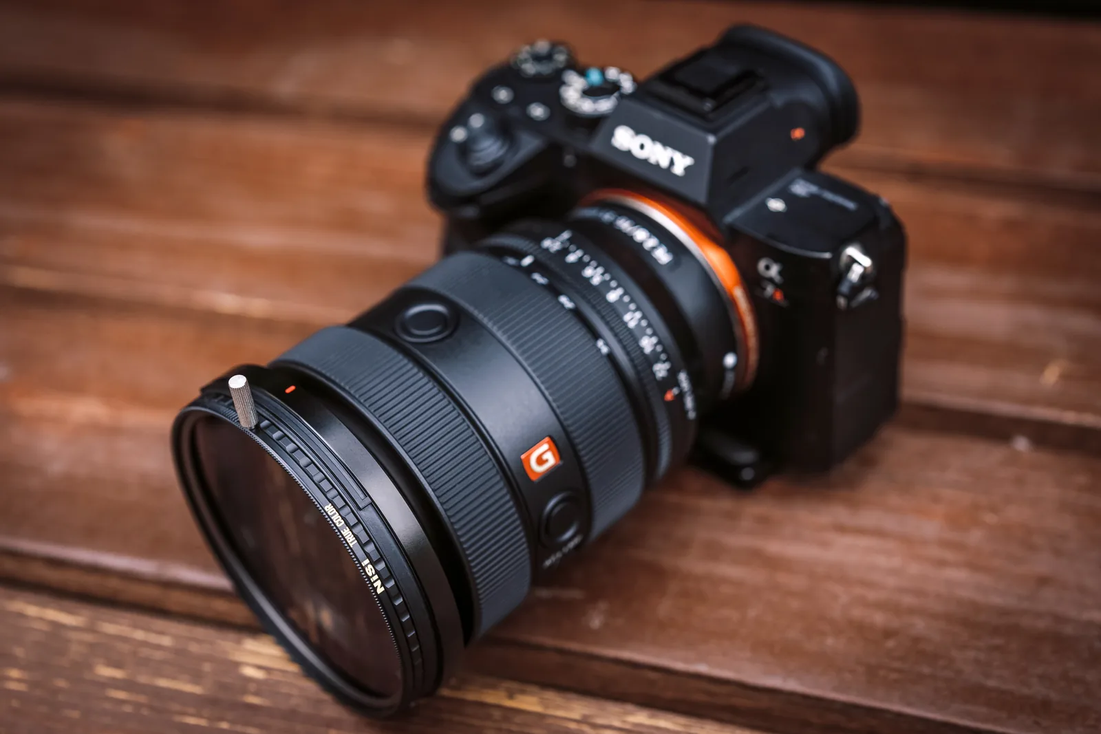 A Sony camera with the brass frame CPL fitted, resting on a wooden bench