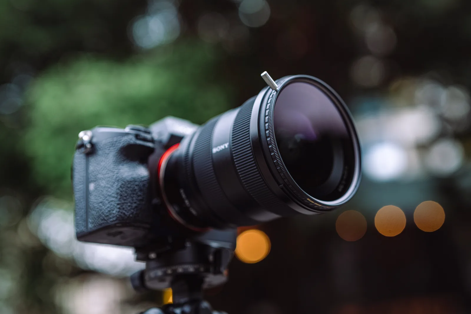 A Sony camera on a tripod with the brass frame True Color CPL fitted, against evening bokeh